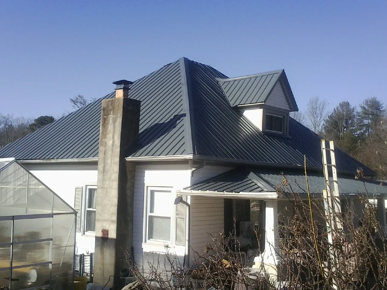 Dark blue standing seam metal roof on a white farmhouse with dormer — Slate & Tile Roof Repair by Roofing Brothers in Boligee