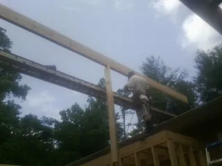 Carpenter setting a ridge beam over a new addition frame — Ice Dam Removal by Roofing Brothers in Boligee