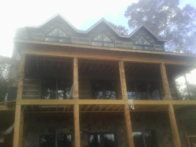 Dormers and porch framing on a large log home under construction — Roof Coating work by our crew in Boligee