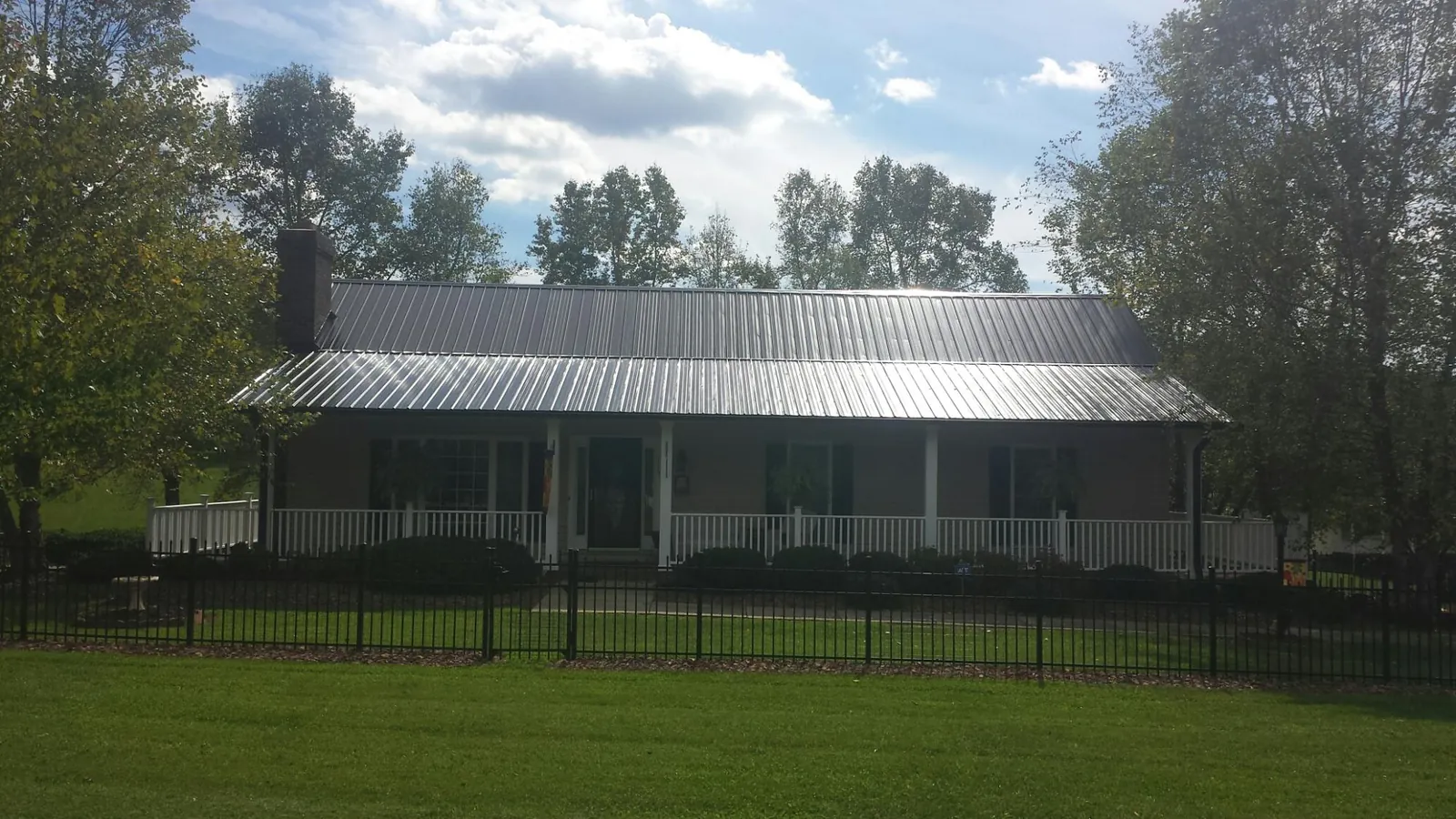 Gray metal roof on a brick ranch with a full width front porch — Gutter Guard Installation work by our crew in Boligee