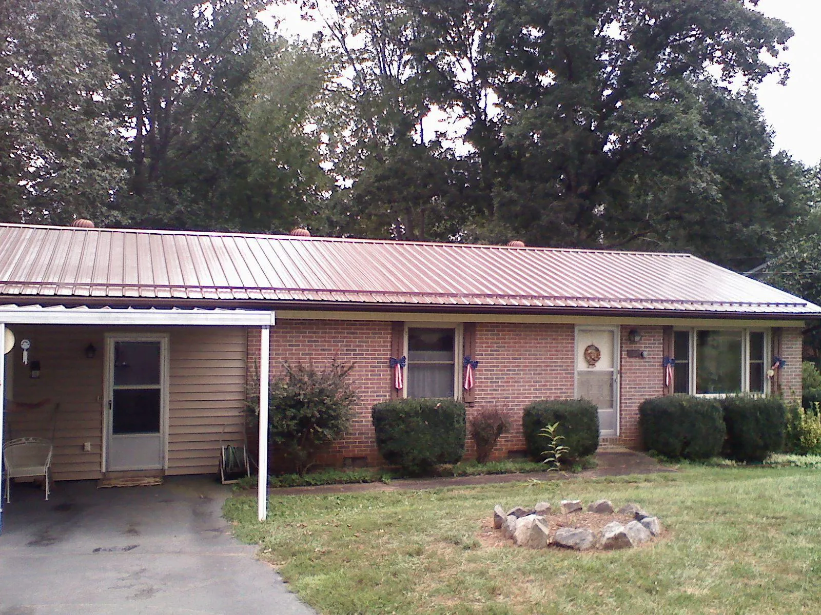 Bronze metal roof and carport on a brick ranch home — Roof Repair work by our crew in Boligee