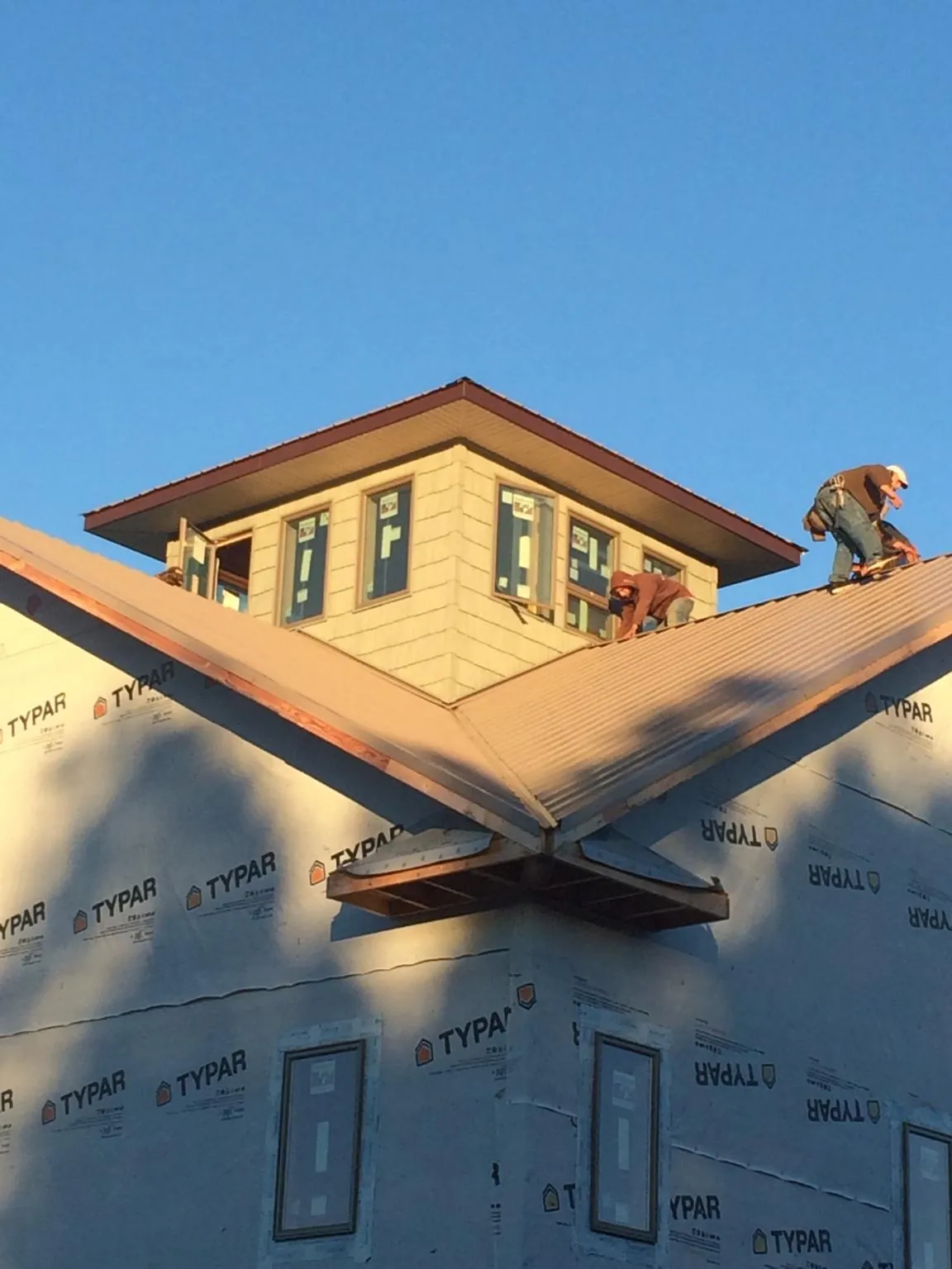Roofers working around a rooftop cupola on a new metal roof at sunset — Roof Waterproofing in Boligee by Roofing Brothers